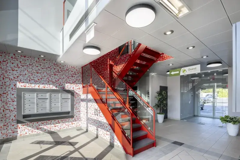 Award-winning Staten Island lobby design, recognized for excellence in interior design, featuring modern corporate interiors, a bold red staircase, and vibrant décor.