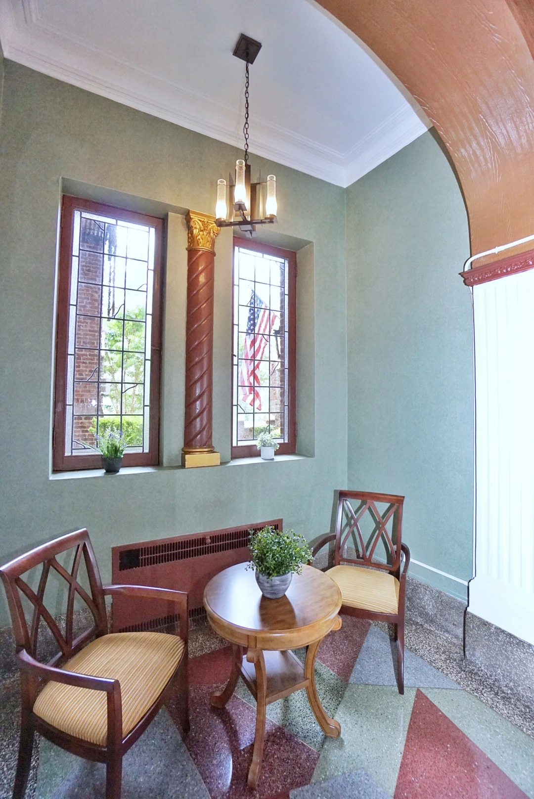 Elegant Staten Island seating vignette featuring a historic lobby design, leaded glass windows, and gold-leaf column details.