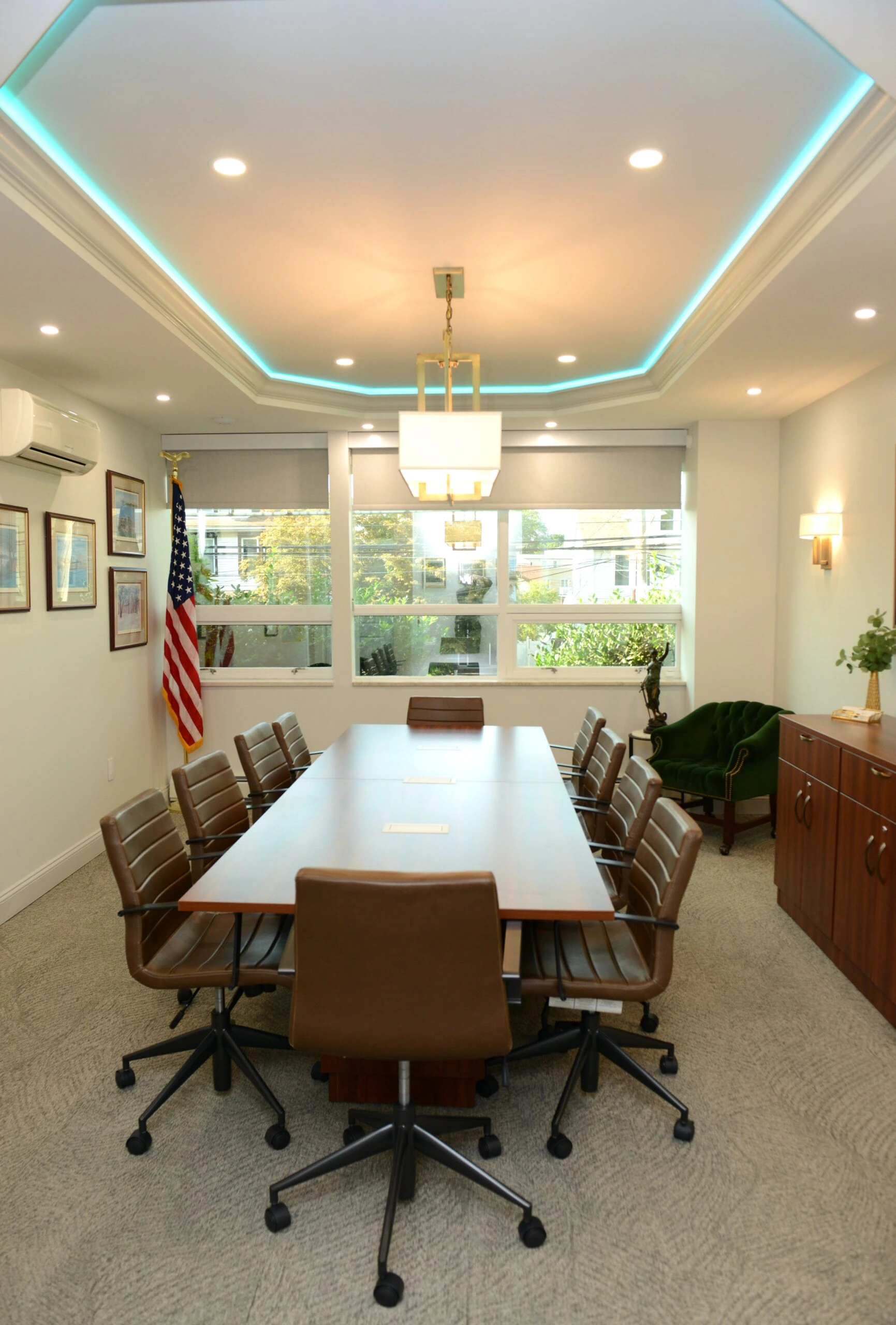 Staten Island law firm conference room with natural light, historical photographs of court buildings and landmarks, rectangular chandelier, LED cove lighting, rich leather chairs, blending tradition with modern functionality.