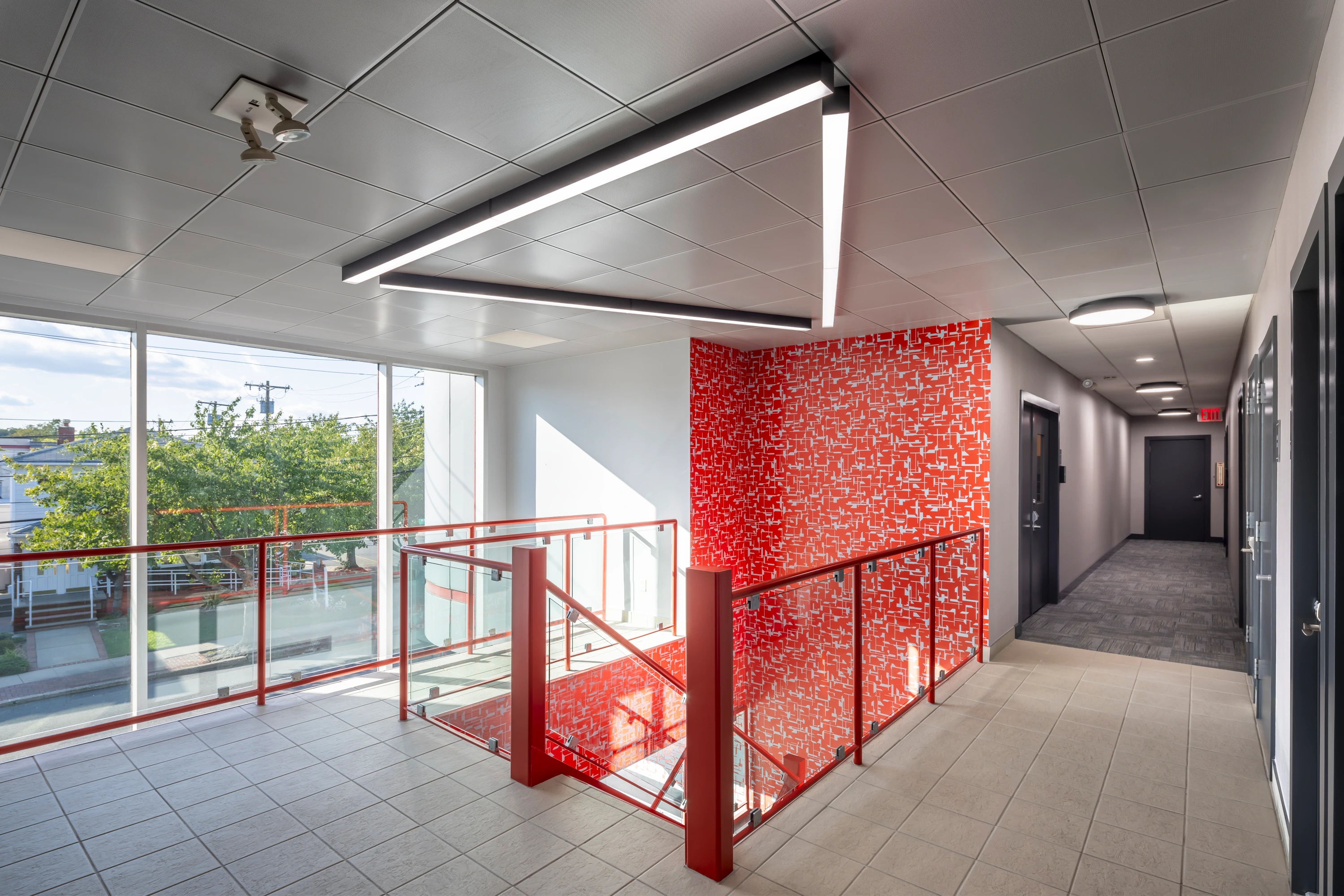 "Staten Island office design featuring a Chamber of Commerce award-winning red geometric accent wall, modern interior materials, and a naturally lit workspace.