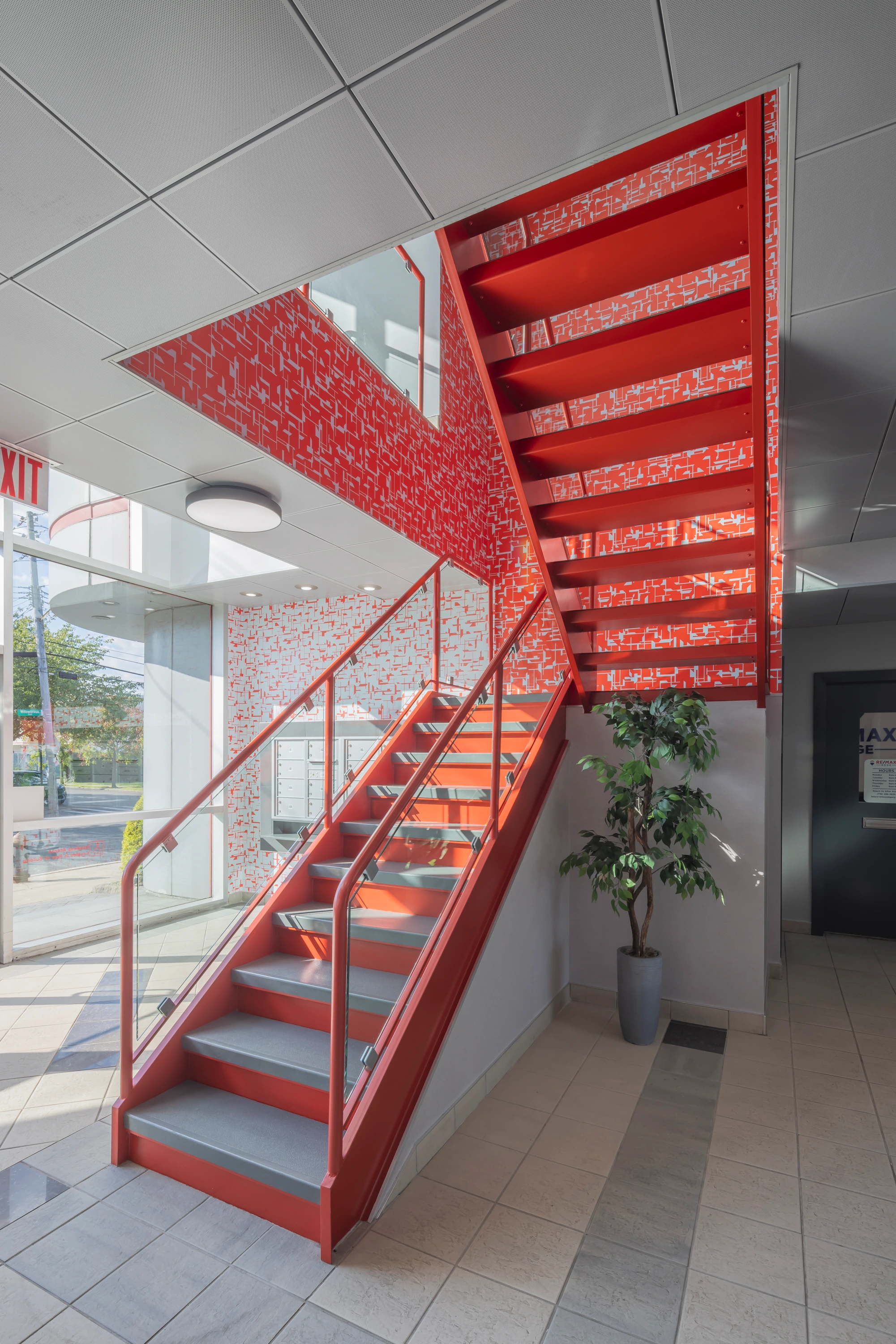 Award-winning Staten Island lobby design, recognized for excellence in interior design, featuring modern corporate interiors, a bold red staircase, and vibrant décor.