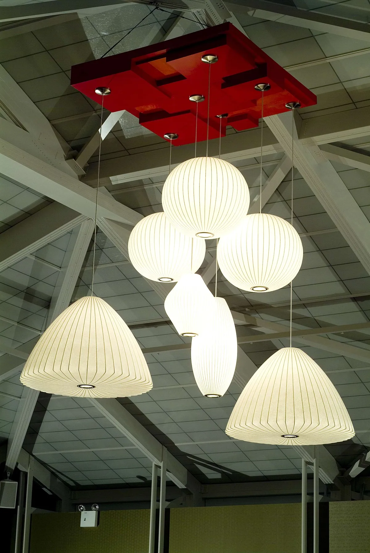 Close-up of modern pendant lighting with Nelson Bubble Lamps hanging from a red ceiling mount in a stylish tea house banquet room.