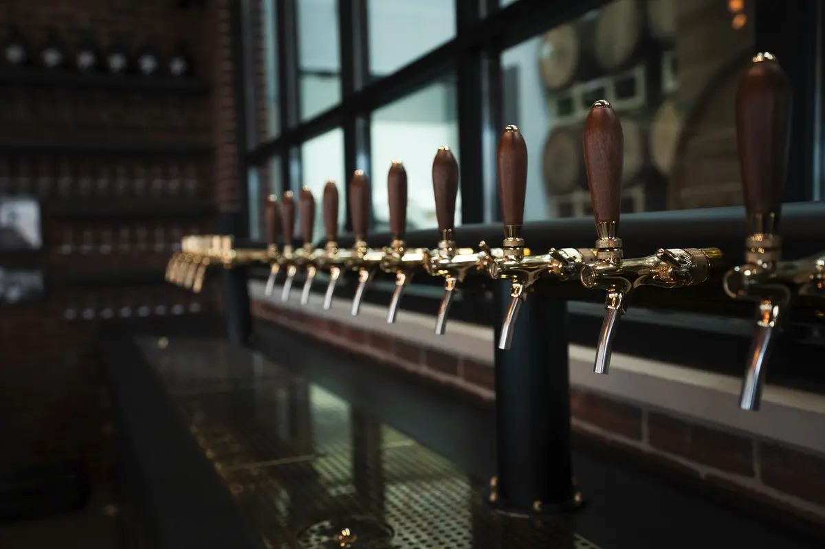 Brewery bar with polished metal beer taps, industrial design, and a warm ambiance in Staten Island’s craft beer scene.