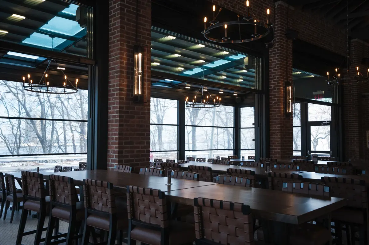 Industrial dining space with reclaimed wood tables, leather-woven chairs, rustic brick walls, and modern restaurant design.