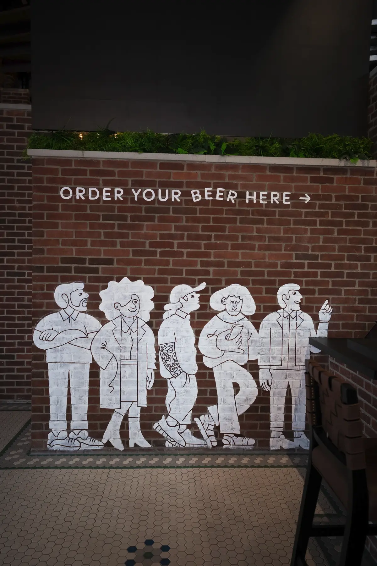 Brewery drums are set against a brick wall mural, creating a craft beer bar with an industrial design and unique ambiance.