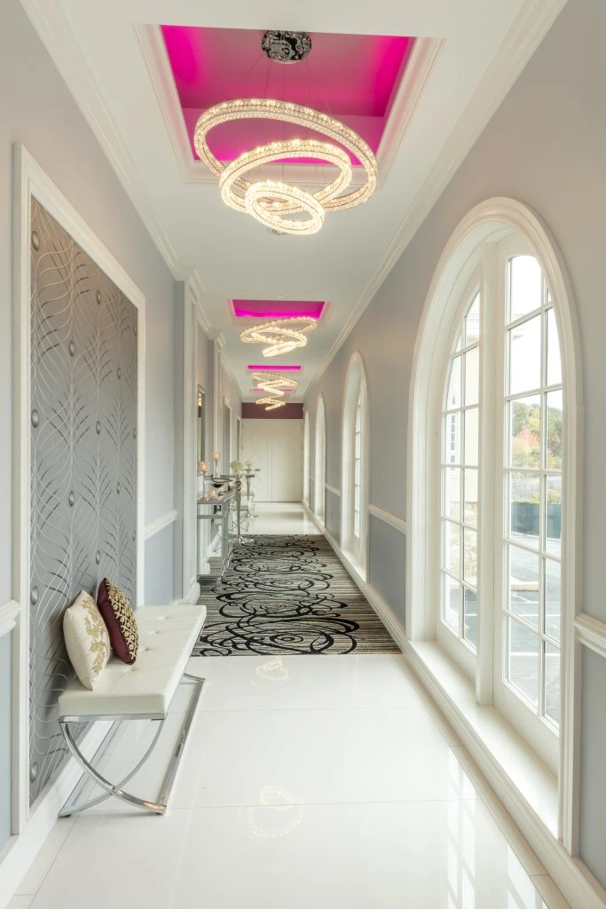 Hallway with porcelain floors, modern chandeliers, arched windows, and a designer rug, creating a timeless ambiance.