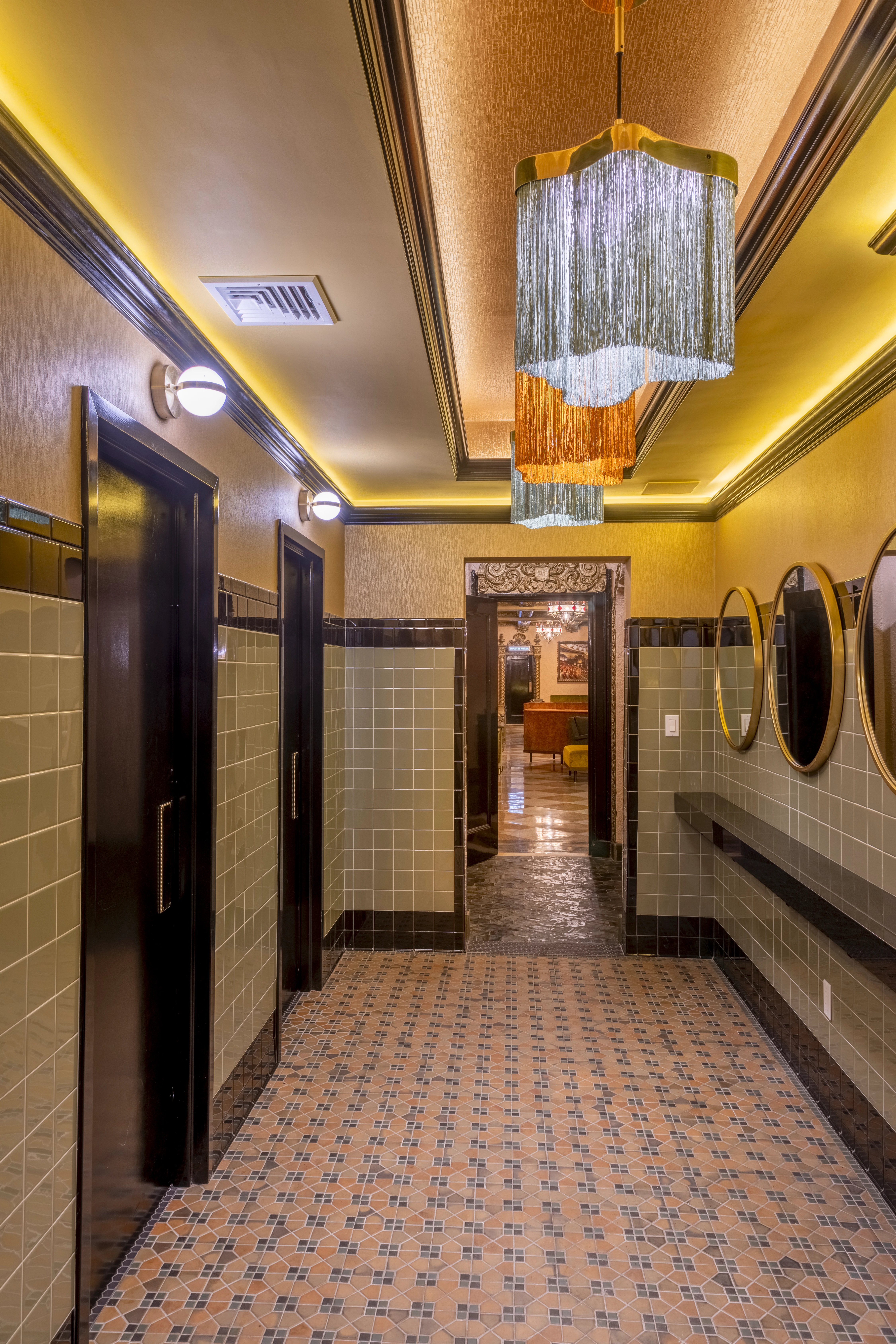 Vintage-inspired unisex lounge restroom with green tiles, moody lighting, and luxury design in a renovated historic theater.