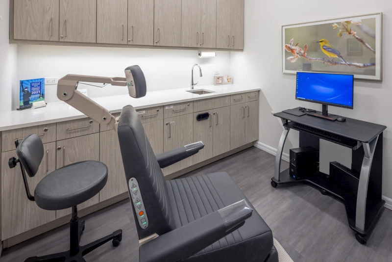 Modern exam room with ergonomic seating, professional treatment chair, calming bird artwork, and a patient-centered design.