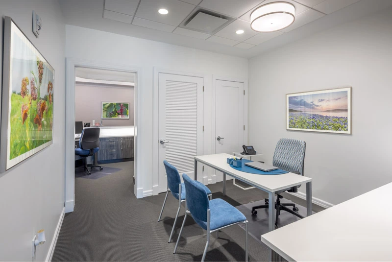 Administrative office with sleek white desks, blue chairs, serene landscape artwork, and a professional yet inviting atmosphere.