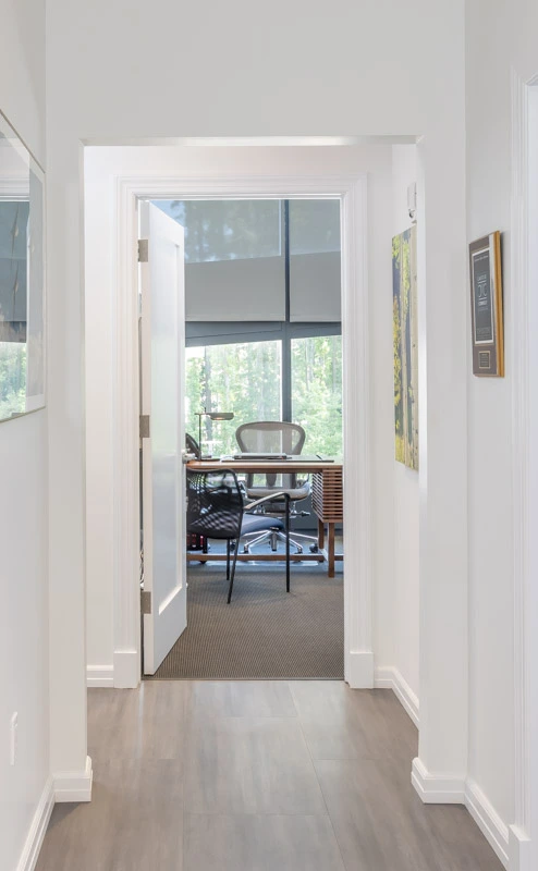 Minimalist office hallway with natural light, clean lines, and contemporary décor leading to a bright workspace.