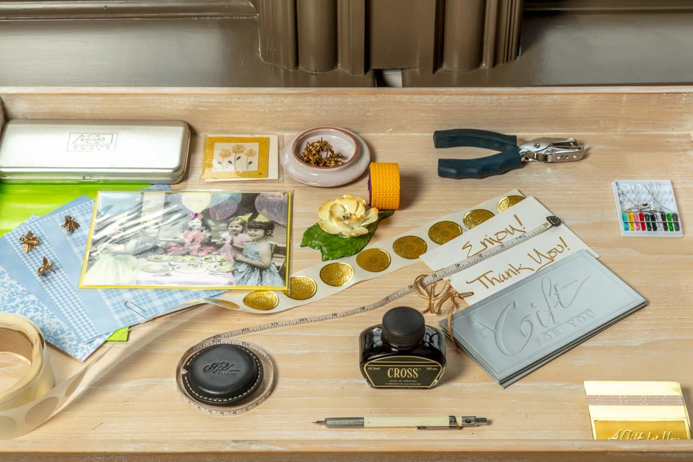 Arranged craft table featuring a vintage ink bottle, handwritten notes, golden stickers, and DIY tools.