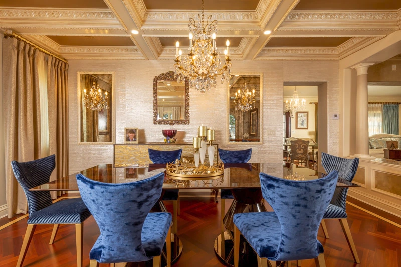 Velvet blue dining chairs, an elegant chandelier, and classic interiors for a luxurious dining room design.